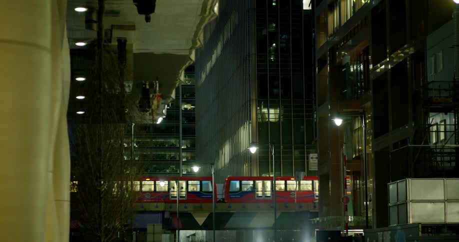 Train passing through a viaduct amidst buildings in a metropolis at night