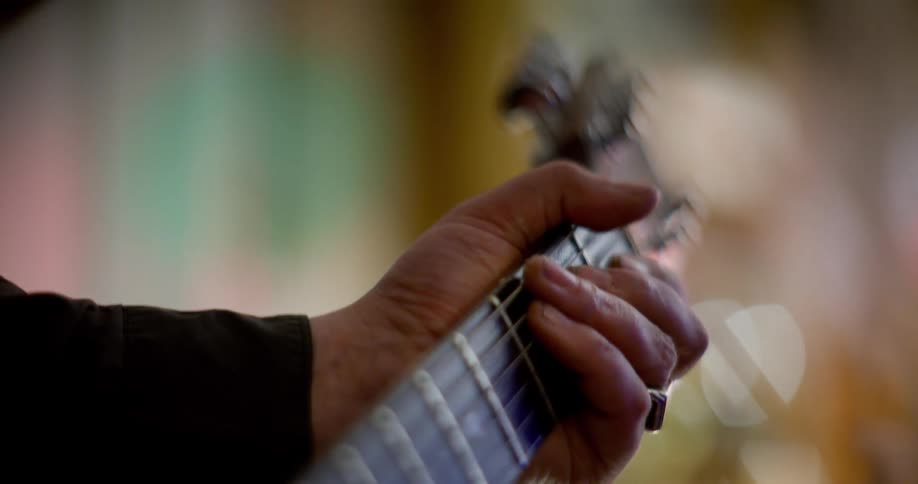 A human hand holding the neck of an electric guitar