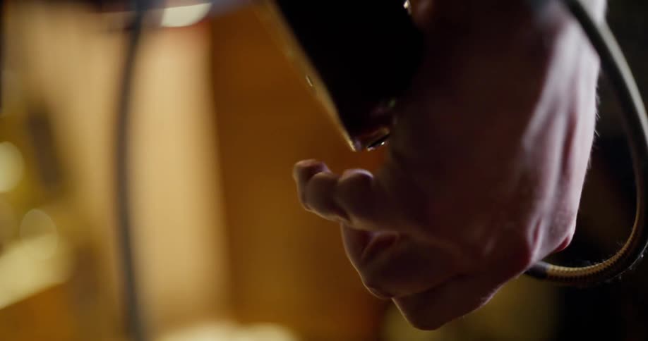 A hand plugging in an electric guitar