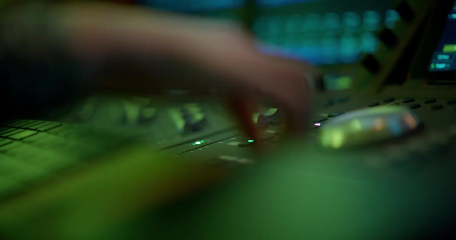 Hand adjusting sliders on a recording studio mixing desk