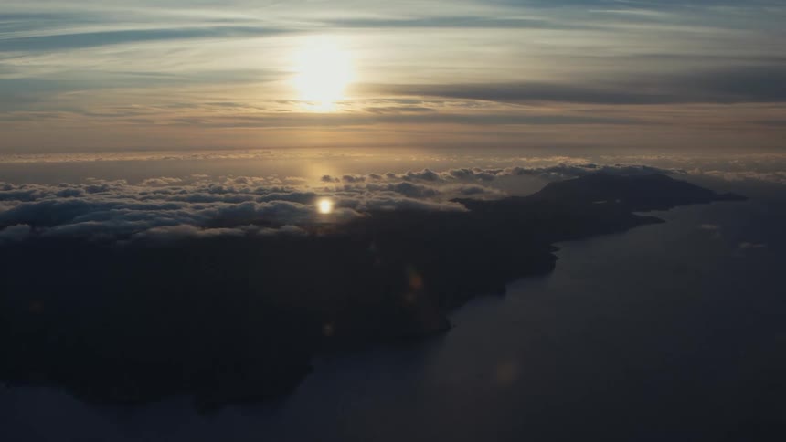 The sun and a cloud bank over an island