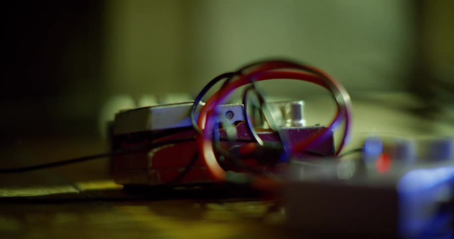 A close up of a foot pressing an electric guitar effects pedal