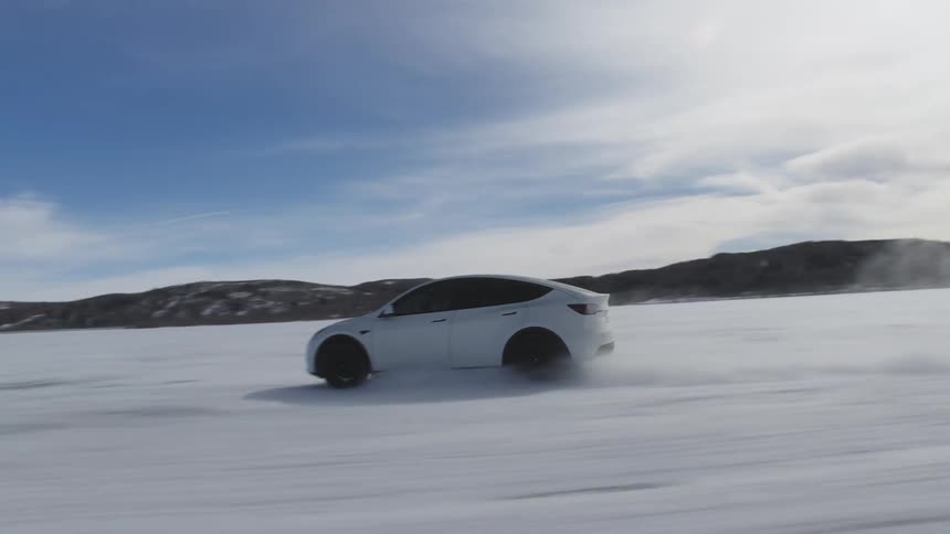 A white car driving over a remote region with snow on the ground