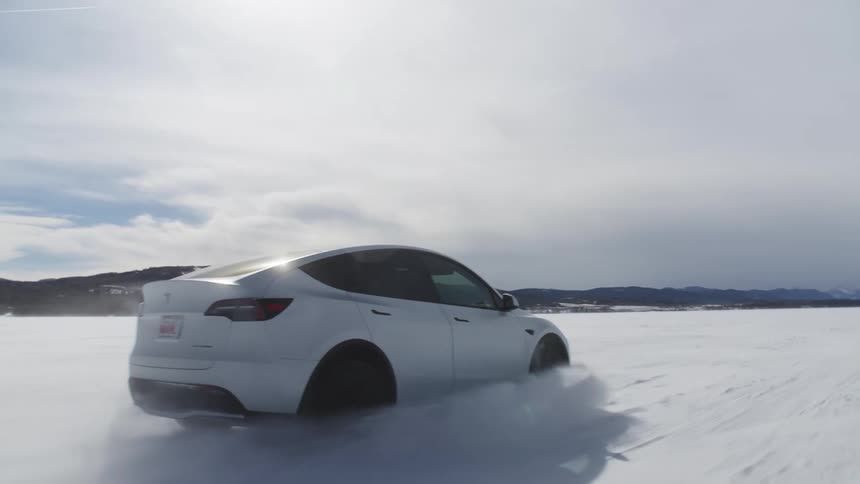 White and sporty tesla at high speed on a snowcovered ground on a cloudy day