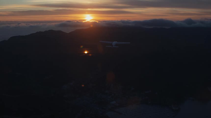 A small private plane flying over an island on a sunny day