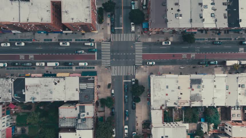 An aerial view of a street intersection with several crosswalks and cars parked on the sides