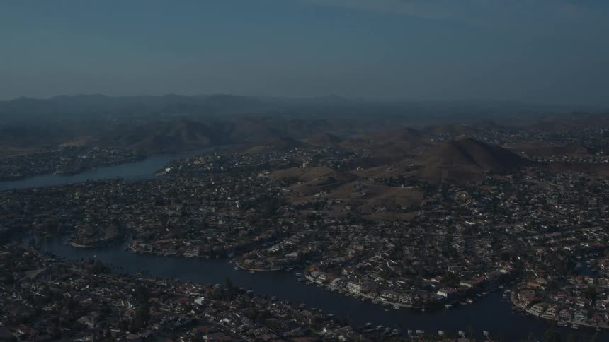 An aerial view of a city with many houses and a large river running through the middle