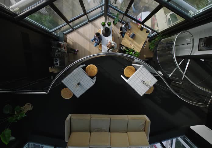Top view of a commercial building with workers at office desks and walking down the stairs