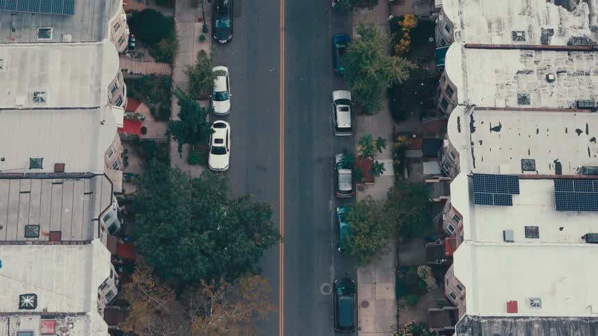 An aerial view of a city street with cars parked on both sides of the road