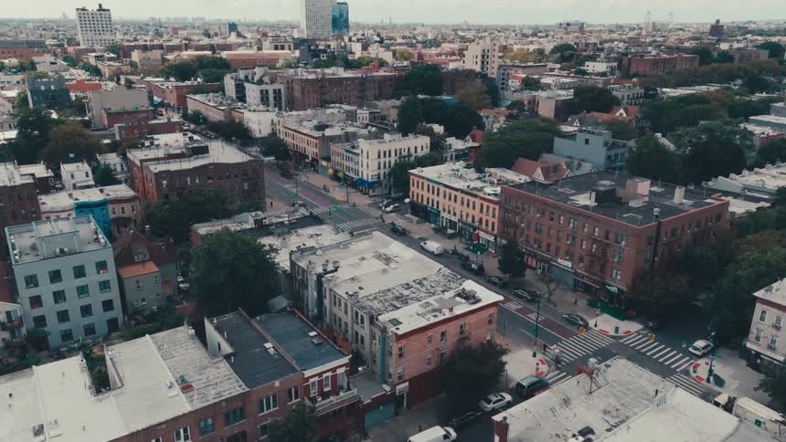 An aerial view of a street with several cars in the middle of an urban region of a city with several mediumsized buildings