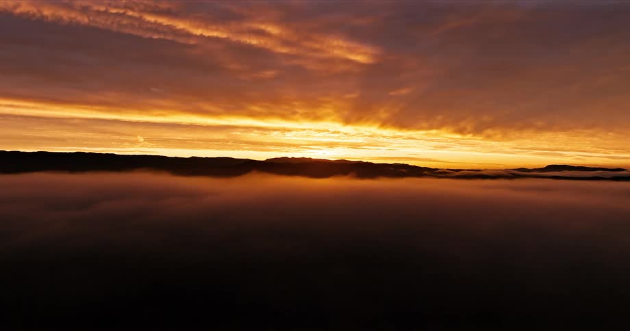Scenery above the fog with an orange sunrise sky on the horizon under an urban city
