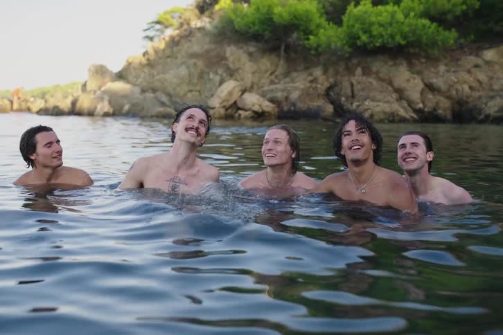 A group of guys look and laugh while treading water