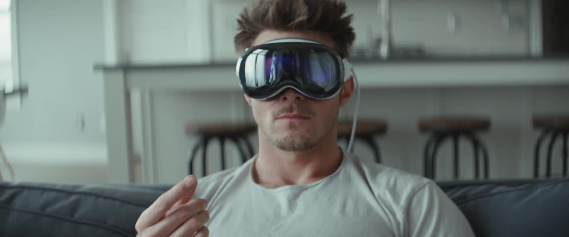 Portrait of a man sitting on the sofa in the living room and using virtual reality glasses