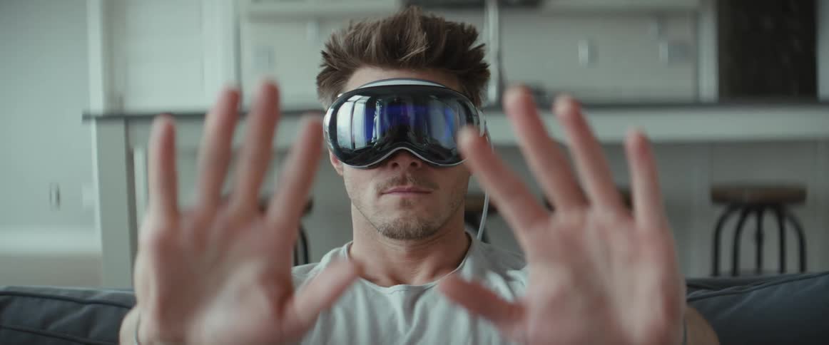 Man sitting on sofa wearing virtual reality glasses and moving his hands