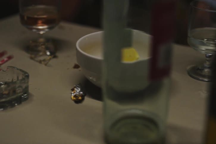 Some men are sitting in front of a table with drinks and are smoking and talking