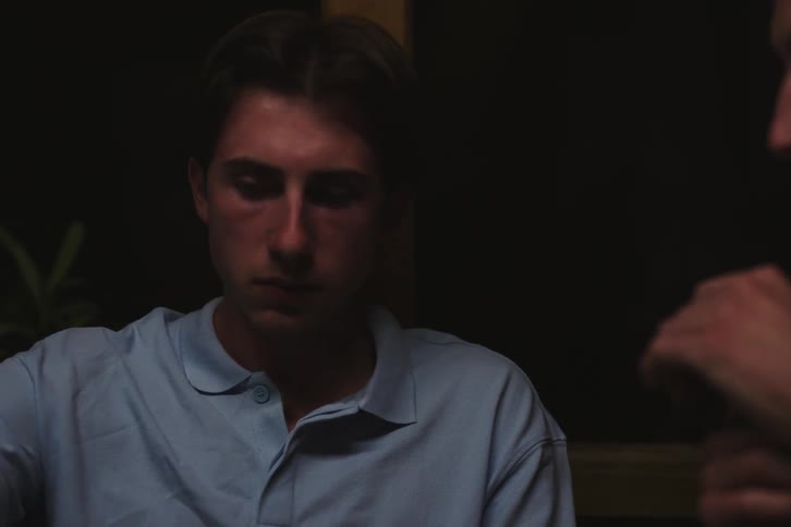 A young boy with a mustache is talking to another boy who is chewing something