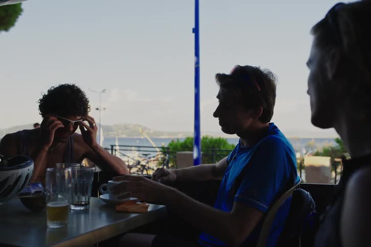 Four male friends drinking and chatting while at seaside restaurant
