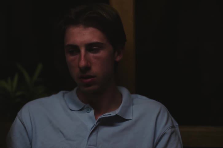 A young speaks to a friend while eating and getting ready to drink