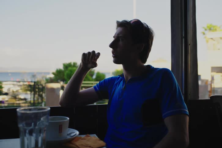Young friends sitting at a cafeteria table talk drink and smoke