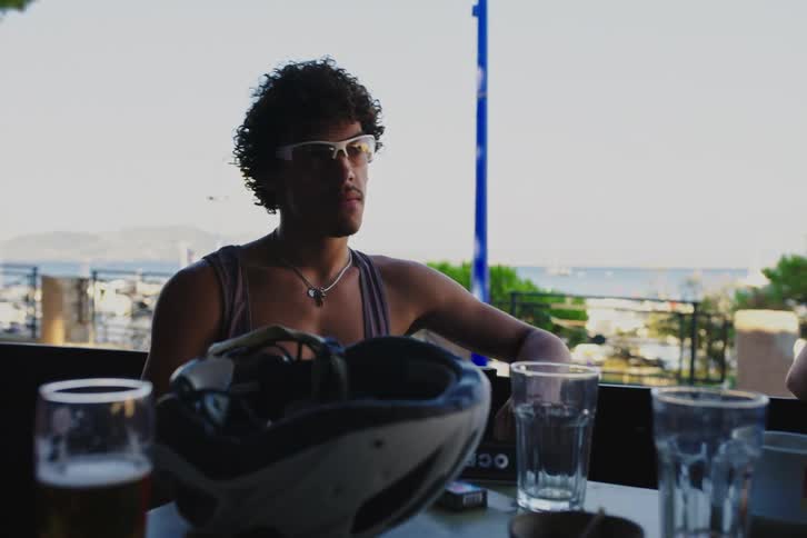 Friends sitting at a table by the sea talking and drinking