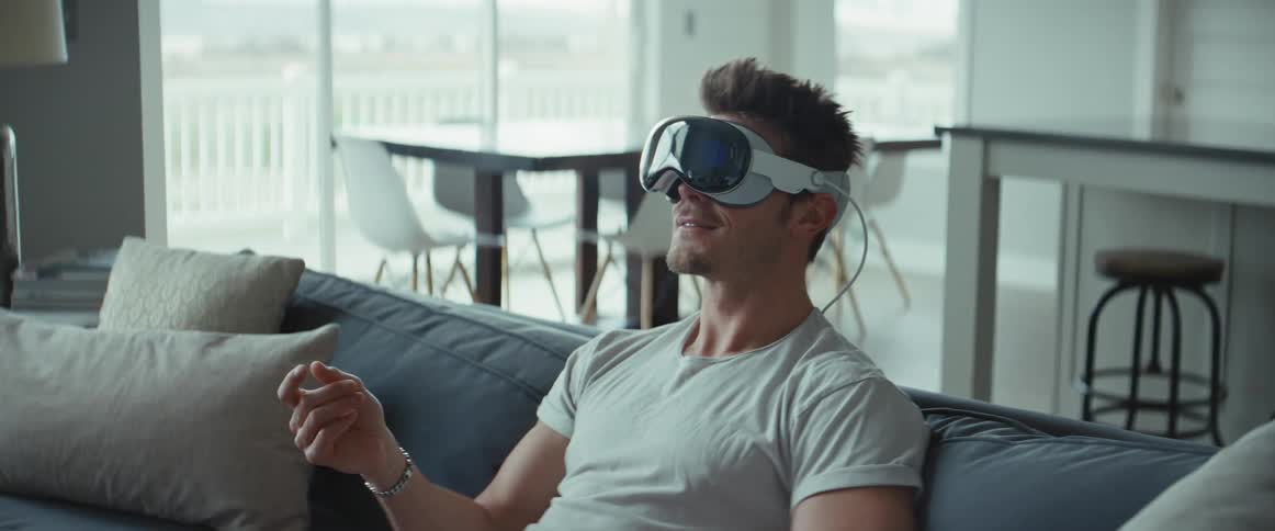 A man sits on his couch using virtual reality goggles