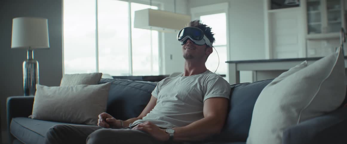 A man sitting on a couch smiling while wearing vr glasses