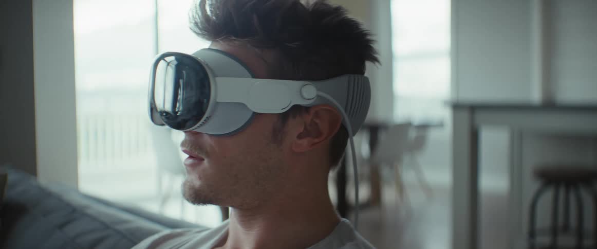 Man sitting on sofa smiling wearing virtual reality glasses
