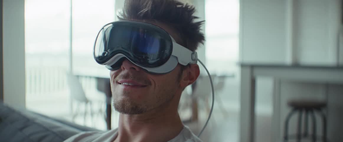 Man sitting on living room couch while wearing a vr headset smiles