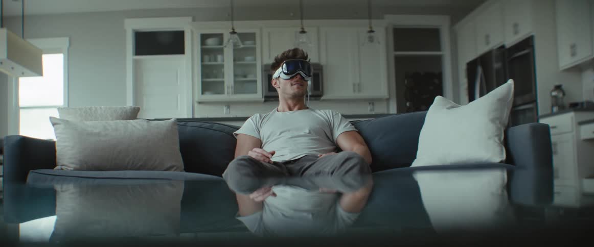 Man sitting in the living room smiling while using a virtual reality glasses