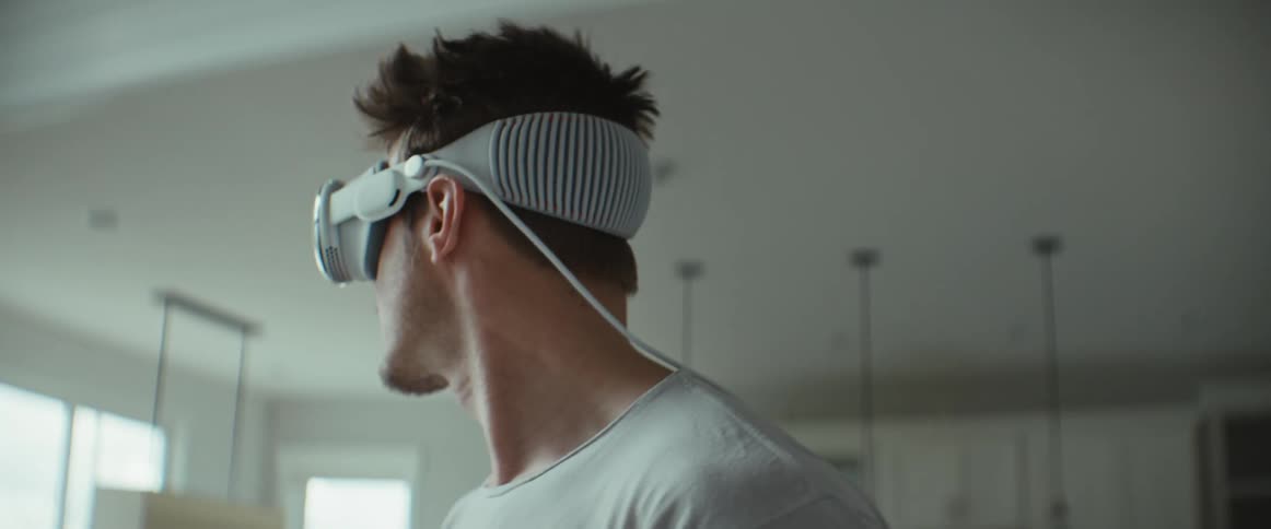 The face of a man who is standing and is wearing a white virtual reality glasses and is smiling
