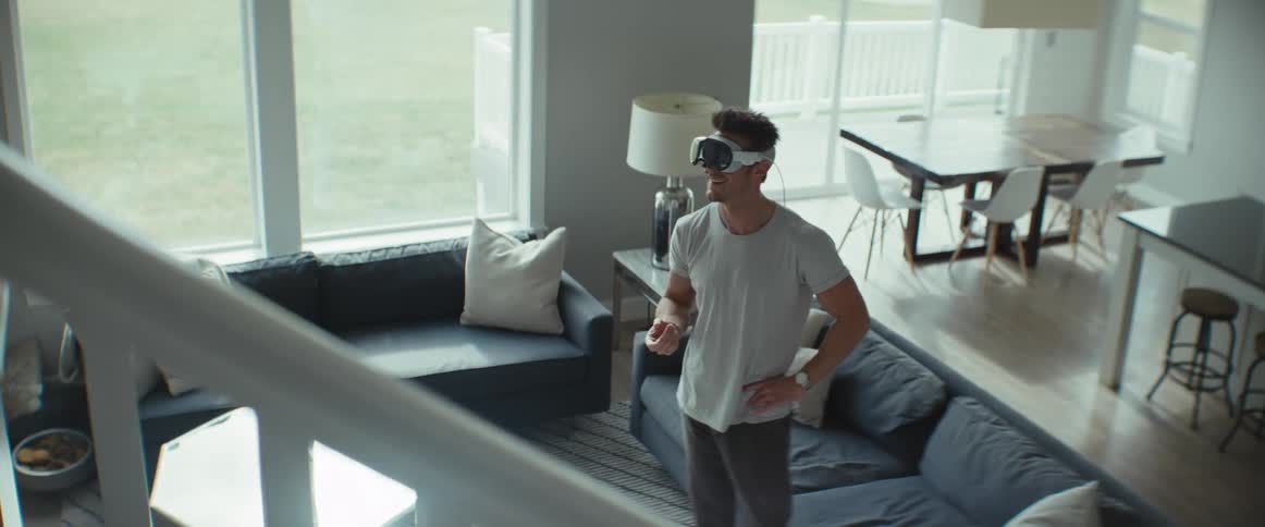 Man standing in living room moving around while wearing virtual reality glasses