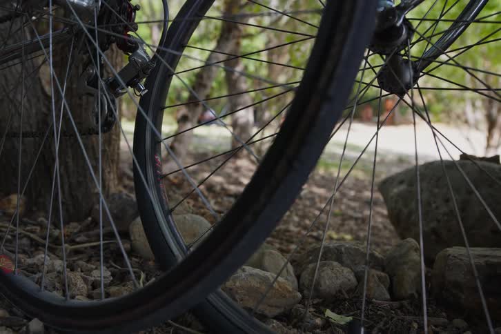 Two wheels of two bicycles are stopped on a dirt floor with stones