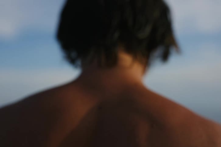 Shirtless man with his back jumping towards the sea
