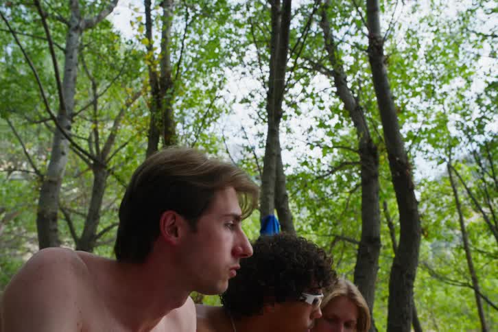Three men and friends are gathered while they are eating and playing something in front of them in a region in the middle of the forest