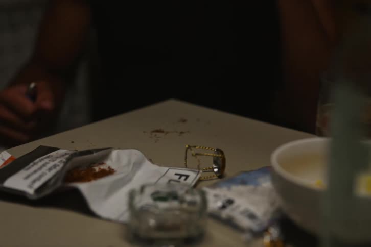 Men sit talking and smoking at table holding tobacco and alcohol