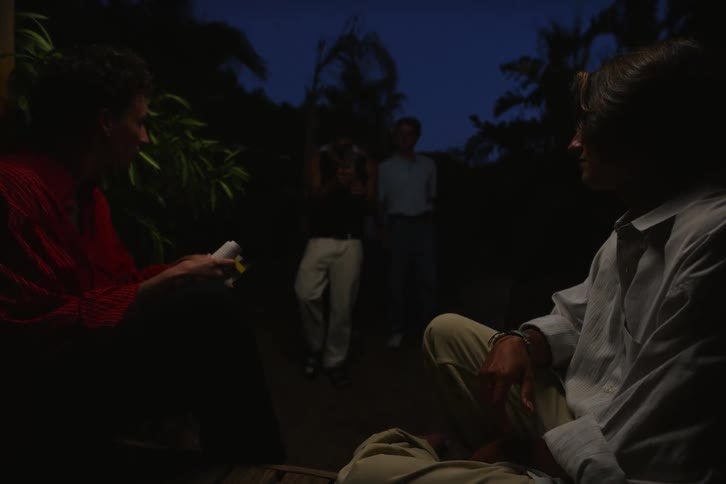 Two men are sitting on a wooden balcony and then three other bodies appear and start talking and interacting with them