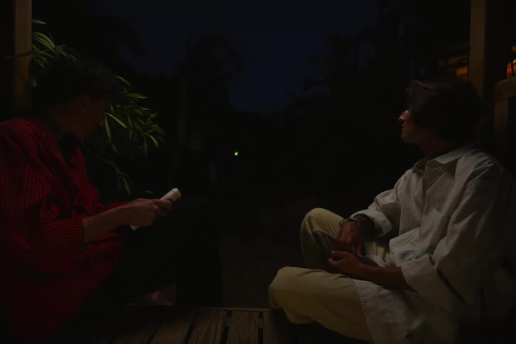 One boy is playing the guitar while the other is reading a book when three other boys arrive