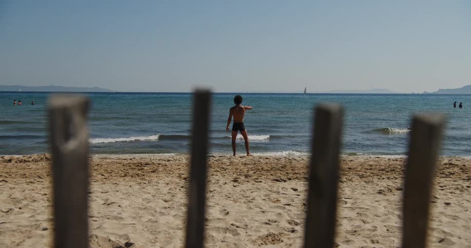 Man in swimming trunks on the sand of the beach in front of the sea dancing