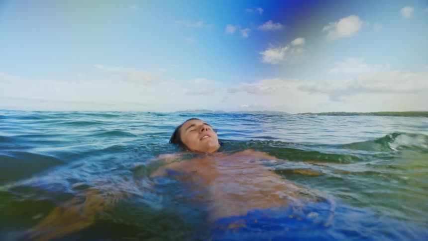 A young man swimming and floating in the ocean