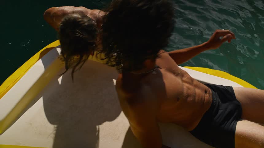 Two guys laying on a raft floating around