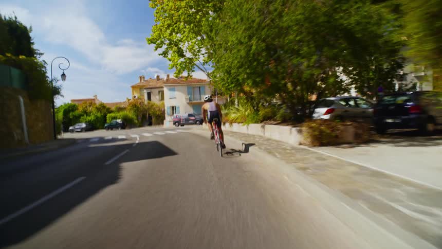 A bicyclist rides down a road in a suburban area