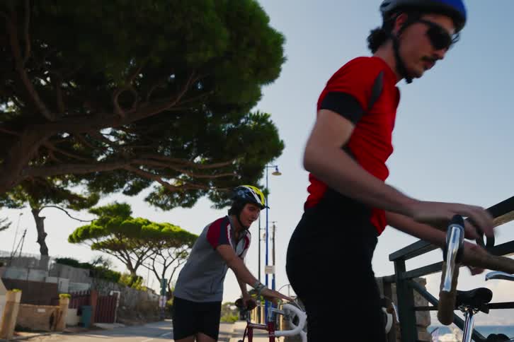 Two cyclists stopping and putting their bikes on the side of the street and walking