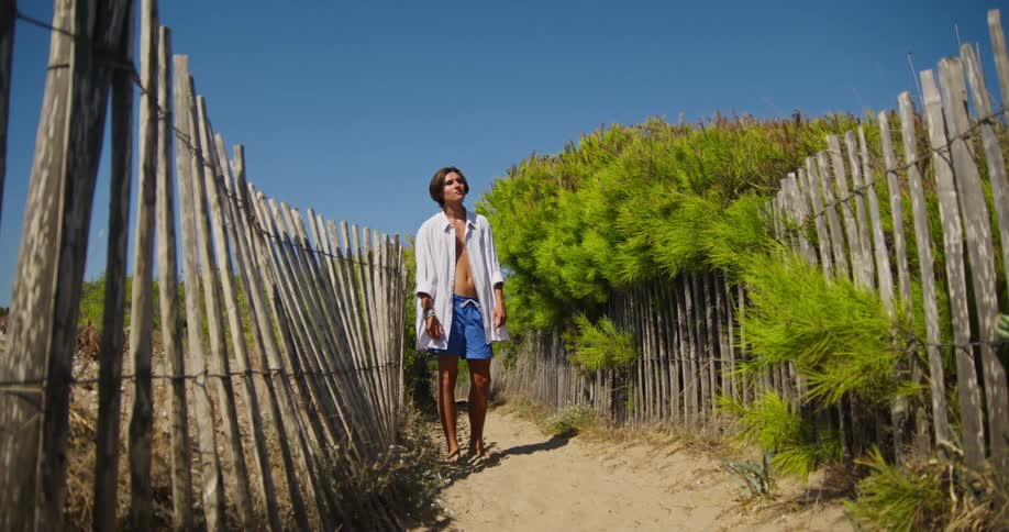 Young man walks down a pathway and stops he stares at something then walks forward