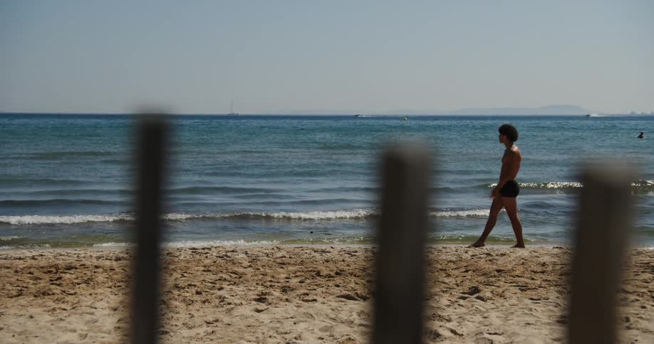 Man in swimming trunks dancing in the sand at the beach