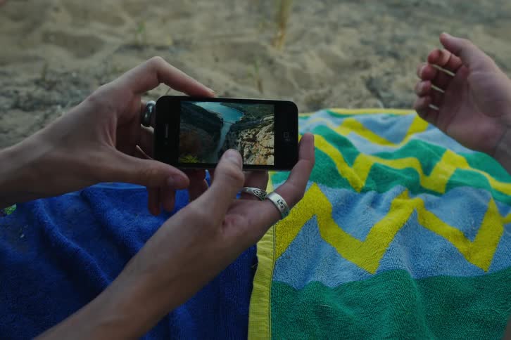 Hands holding a cellphone zooming in on a photo