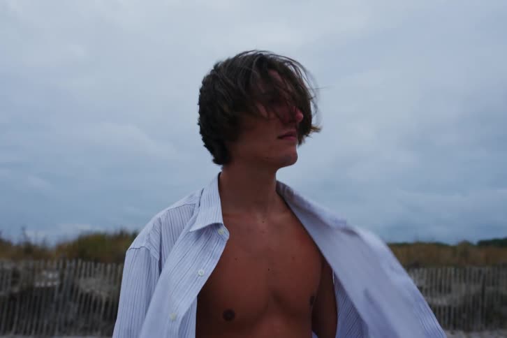 Two men on the sand of the seaside beach on a summer day looking at each other with one of them dancing