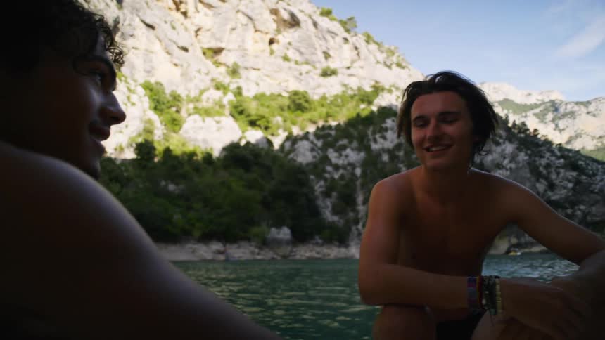 Two male friends hanging out on the lake talking