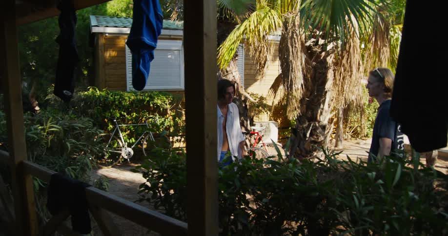 Friends on the porch of their house in a natural environment with one of them with a bottle of drink and others walking and talking