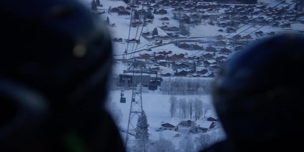 Three people waiting for a cable car to take them to a ski lodge on a snowy mountain