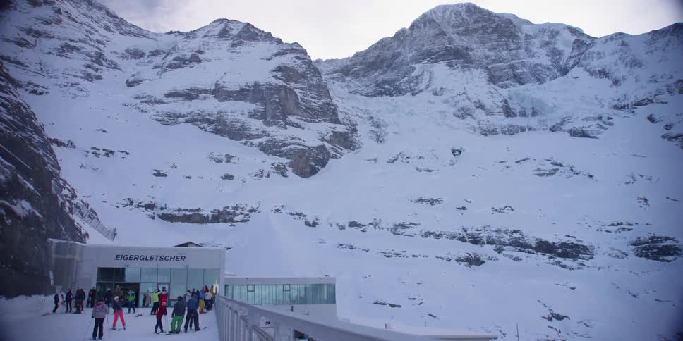 A ski resort near the top of a snow covered mountain filled with tourists